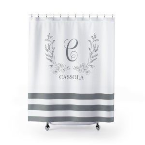 May include: White shower curtain with gray stripes and a floral wreath design featuring the letter "C" and the name "CASSOLA" in a gray font.
