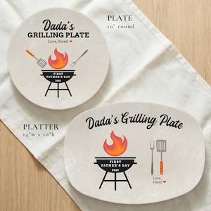 May include: Two beige ceramic plates with grilling-themed designs. One is round, 10 inches in diameter, and the other is an oval platter, 14 inches wide and 10 inches high. Both feature the text "Dada's Grilling Plate" and "First Father's Day 2026".
