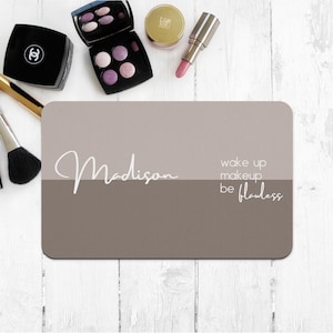 May include: A light brown makeup mat with the text "Madison" on the top half and "wake up makeup be flawless" on the bottom half.