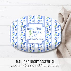 May include: Oval serving platter with a blue and white watercolor design. The platter features vertical blue stripes and repeating Mahjong tile illustrations. Text on the platter reads "Bams, Craks & Snacks at Laura's". The words "Mahjong Night Essential" are below.