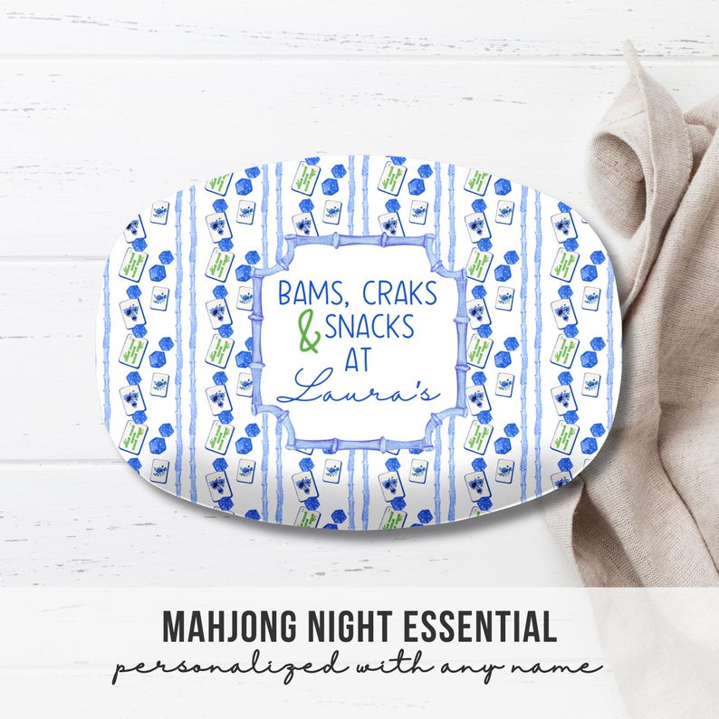 May include: Oval serving platter with a blue and white watercolor design. The platter features vertical blue stripes and repeating Mahjong tile illustrations. Text on the platter reads "Bams, Craks & Snacks at Laura's". The words "Mahjong Night Essential" are below.