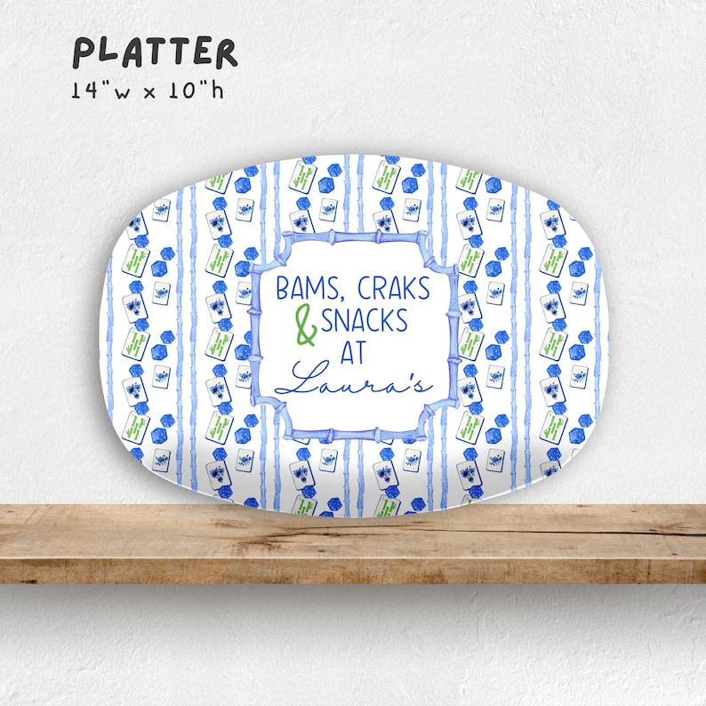 May include: Oval platter with a blue and white striped pattern and floral accents. The platter is 14 inches wide and 10 inches high. Text on the platter reads "BAMS, CRAKS & SNACKS AT Laura's".