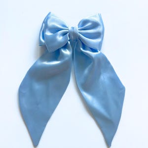 May include: A light blue satin bow with long tails. The bow is tied in a classic style with the tails extending out to the sides.