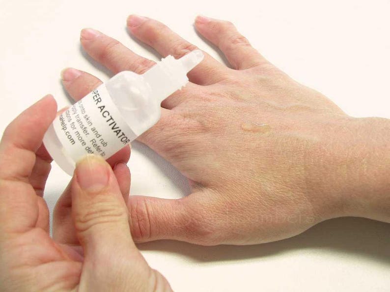 K&ouml;nnte beinhalten: Eine transparente Plastikflasche mit der Aufschrift "SUPER ACTIVATOR" wird &uuml;ber einer Hand gehalten. Die Flasche hat ein wei&szlig;es Etikett mit schwarzem Text. Eine kleine Menge Fl&uuml;ssigkeit ist auf der Hand sichtbar. Der Hintergrund ist eine schlichte wei&szlig;e Oberfl&auml;che.
