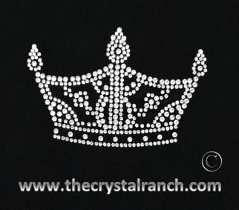 May include: A rhinestone crown design with a pointed top and two side points. The crown is made of clear rhinestones.