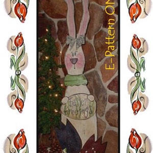 Può includere: Un modello di coniglio pasquale in legno con orecchie lunghe, una sciarpa verde e un cartello che dice "Easter Greetings". Il coniglio è in piedi davanti a un muro di pietra con un piccolo albero di Natale dietro.