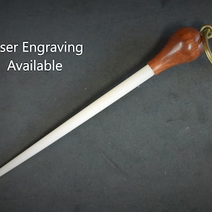 May include: A white wooden conductor's baton with a brown wooden handle and a gold metal key ring.  Laser engraving available.