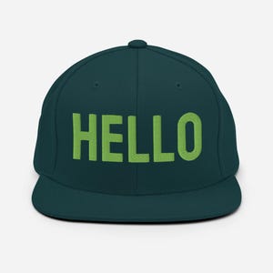 May include: A dark teal baseball cap with the word "HELLO" embroidered in bright green block letters across the front. The cap has a flat brim and a structured fit, suitable for casual wear.