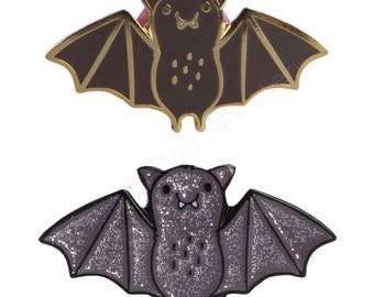Peut inclure: Deux épingles en émail en forme de chauves-souris. Une chauve-souris est brune avec des accents dorés et l'autre est grise avec des paillettes. Les deux chauves-souris ont un visage de dessin animé mignon.
