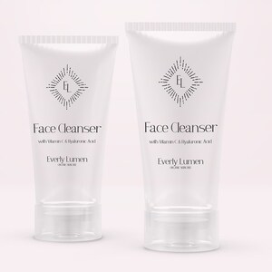 May include: Two white tubes of face cleanser with a black and white logo and text that reads "Face Cleanser with Vitamin C & Hyaluronic Acid Everly Lumen".