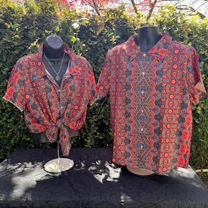 Puede incluir: Dos camisas de manga corta con un estampado geométrico colorido en tonos rojos, naranjas, amarillos, azules y verdes. Las camisas están en maniquíes sobre un fondo de follaje verde.