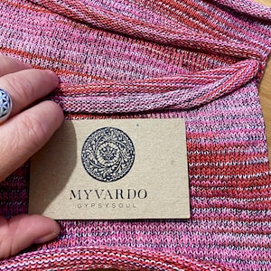 May include: Close-up of a pink and red striped fabric with a brown tag that says "MY VARDO GYPSYSOUL".