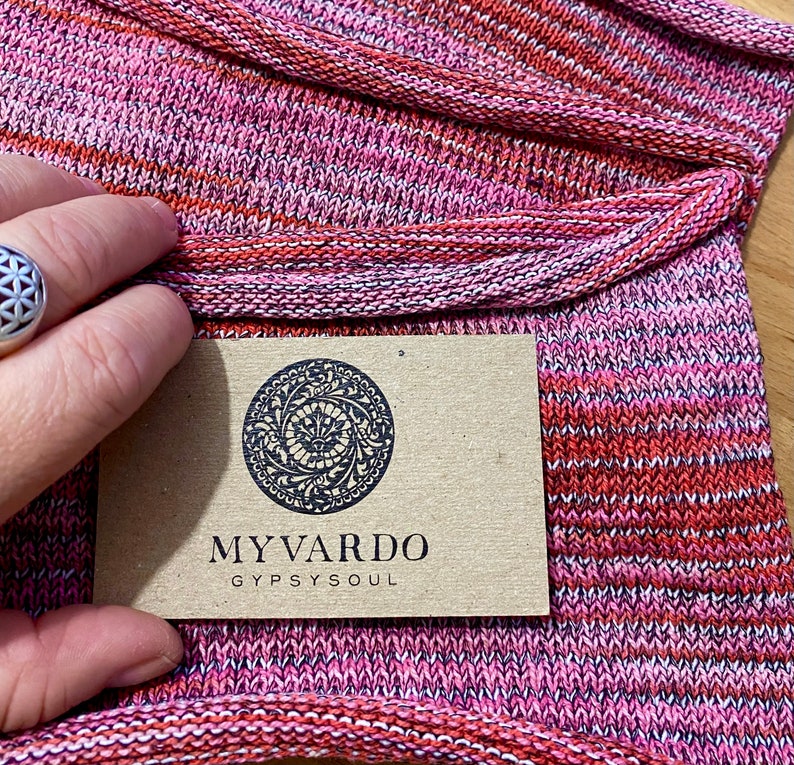 May include: Close-up of a pink and red striped fabric with a brown tag that says "MY VARDO GYPSYSOUL".