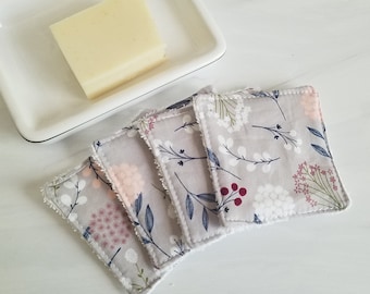 May include: Four gray cotton makeup remover pads with a floral print in shades of pink, white, and blue. The pads are stacked on top of each other.