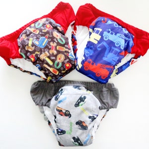 May include: Three training pants with colorful patterns. Two have red trim, one with a brown background and tools, the other with a blue background and construction vehicles. The third has gray trim and a car pattern.