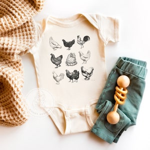 Short sleeve infant bodysuit in a neutral beige color. A graphic of vintage style chickens in black and white printed on the front.