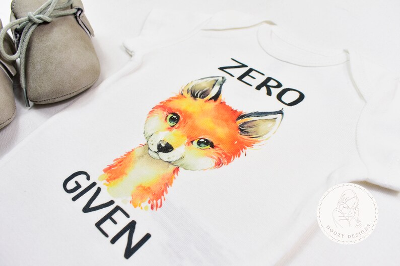 May include: White baby onesie with a watercolor illustration of a fox and the text "ZERO GIVEN".
