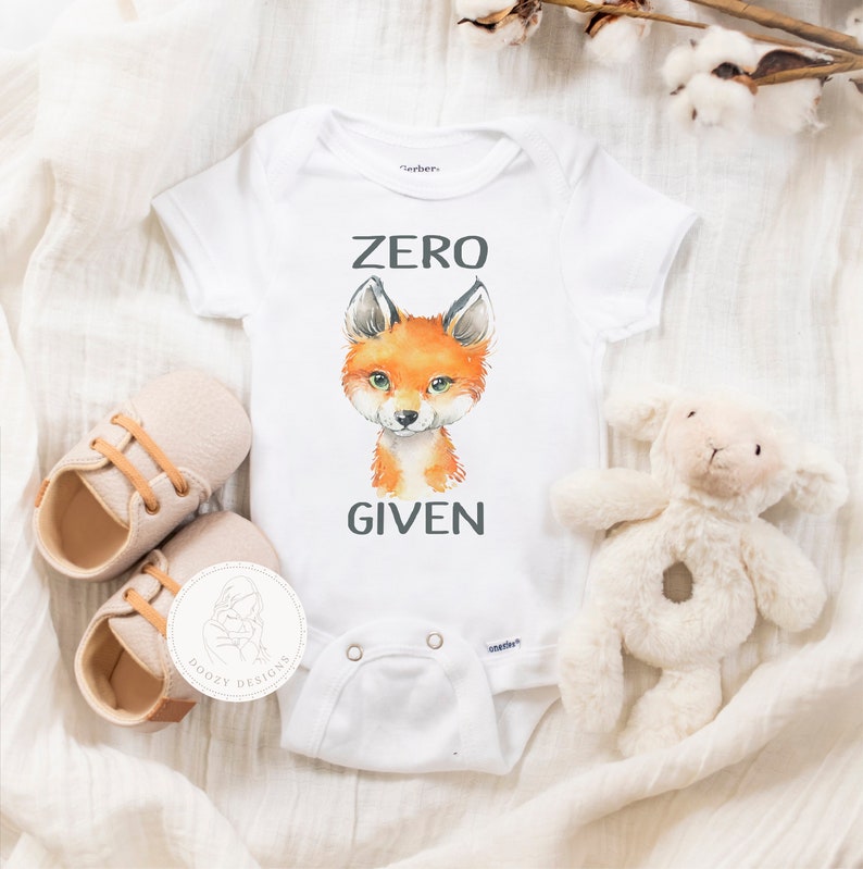 May include: White baby onesie with a fox illustration and the text "ZERO GIVEN".
