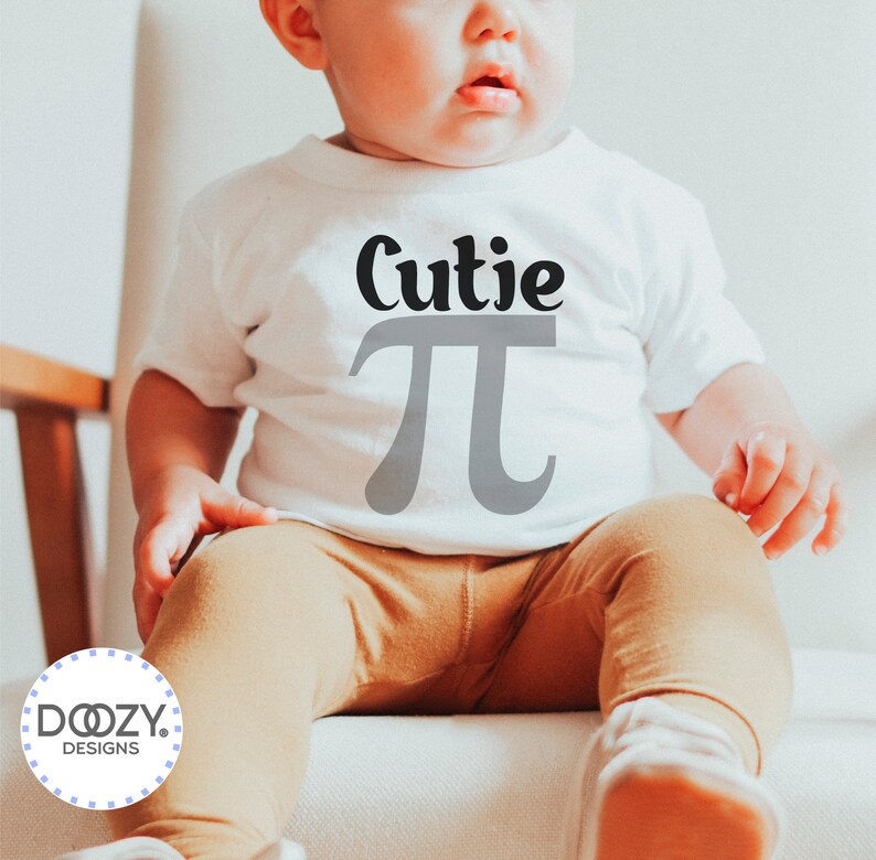 Pu&ograve; includere: Un body bianco per neonato con il testo "Cutie Pi" in lettere nere e grigie. Il body &egrave; indossato da un bambino seduto su una sedia bianca.