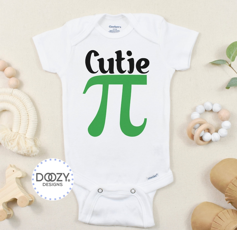 Pu&ograve; includere: Body bianco per neonato con testo nero che dice "Cutie Pi" con un simbolo pi verde.