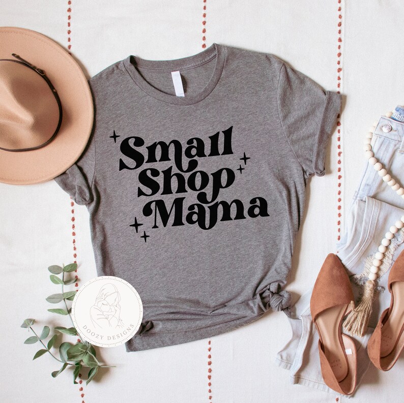 K&ouml;nnte beinhalten: Graues T-Shirt mit dem Text "Small Shop Mama" in schwarzen Retro-Lettern.
