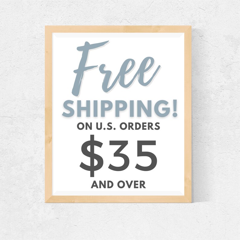 May include: A framed sign with the text "Free Shipping! On U.S. Orders $35 and Over" in a light blue and black font on a white background.