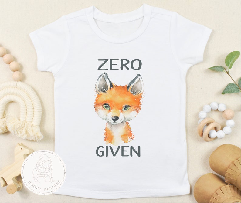 May include: White baby onesie with a fox illustration and the text "ZERO GIVEN" in black.