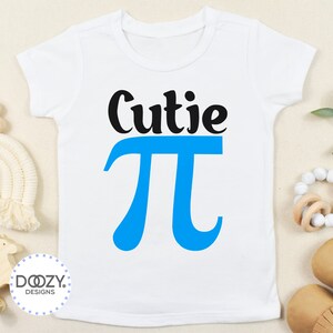 Pu&ograve; includere: Un body bianco per neonato con testo nero che dice "Cutie Pi" con un simbolo pi blu.