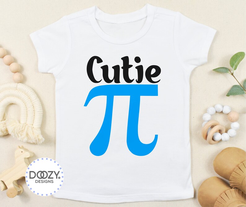 Pu&ograve; includere: Un body bianco per neonato con testo nero che dice "Cutie Pi" con un simbolo pi blu.