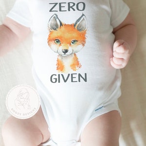May include: White baby onesie with a fox illustration and the text "ZERO GIVEN".