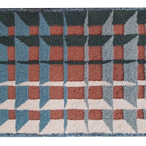 Könnte beinhalten: Ein geometrischer Teppich mit einem sich wiederholenden Muster aus blauen, weißen und braunen Quadraten und Dreiecken.