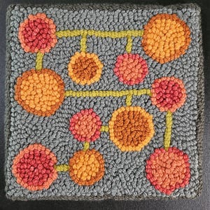 May include: Hand-tufted square rug with a gray background and a pattern of orange and red circles connected by yellow lines. The rug has a textured appearance and a dark gray border.