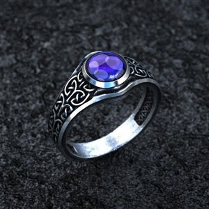 Puede incluir: Un anillo de plata con una piedra preciosa azul engastada en un diseño de nudo celta.