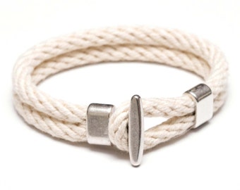 May include: A white rope bracelet with silver metal accents. The bracelet has a simple design and is perfect for everyday wear.