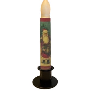 May include: A white candle with a Santa Claus image on it, sitting on a black metal candle holder.