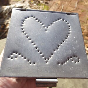 May include: A silver metal box with a hinged lid. The lid has a cutout design of two hearts.
