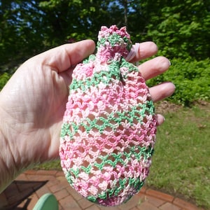 May include: A pink and green crocheted drawstring bag. The bag is made with a delicate openwork pattern.