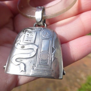 May include: Silver baby rattle with a clock face and the inscription "Record of the Year". The rattle is attached to a clear plastic ring.