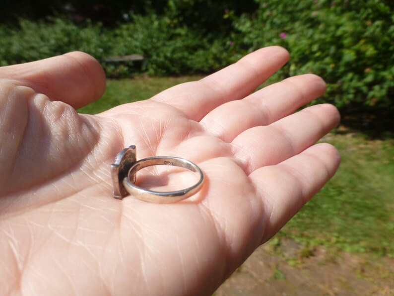 K&ouml;nnte beinhalten: Ein silberner Ring mit quadratischem Design. Der Ring ist auf der Innenseite der Ringschiene mit der Zahl "925" gekennzeichnet.