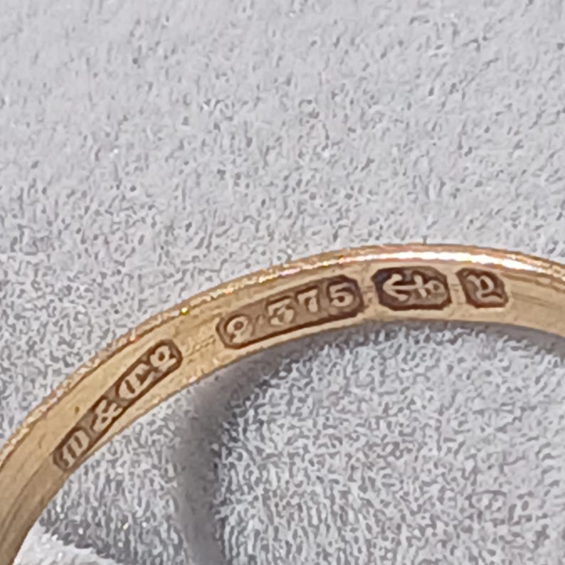 May include: Close-up of a gold ring with the inscription "9375" and an arrow pointing to the left, followed by the inscription "10 & 12".