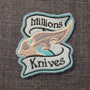 May include: A blue and white embroidered patch with a stylized wing design and the text "Millions Knives".