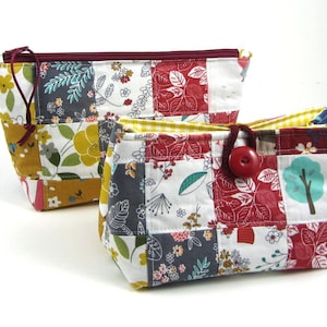 Pode incluir: Duas bolsas de tecido com design de patchwork com padrões florais e de folhas em vermelho, amarelo, cinza e branco. Uma bolsa tem um fecho de correr vermelho escuro, enquanto a outra tem um forro xadrez amarelo e um botão vermelho.