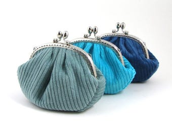 May include: Three small coin purses in different shades of blue. The purses are made of a soft, textured fabric and have a silver metal clasp.