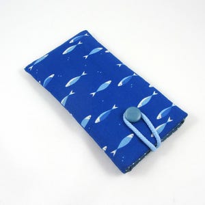 Puede incluir: Funda de gafas de tela azul con un estampado repetido de peces blancos y azules. La funda tiene un cierre de botón con un lazo de cordón azul claro. El interior es un estampado de lunares blancos y azules contrastantes.