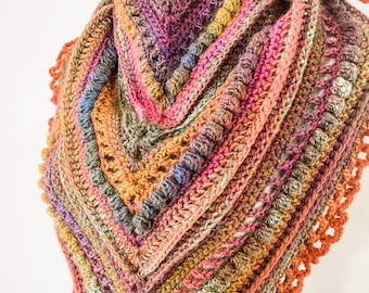 Puede incluir: Un chal de ganchillo hecho a mano, de forma triangular y colorido. El chal presenta una variedad de colores, incluyendo rosa, naranja, morado y verde, con un patrón de puntadas texturizadas. Los bordes están acabados con un borde decorativo festoneado.