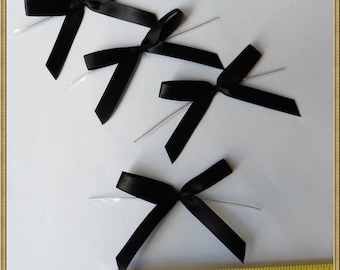 May include: Four black satin ribbon bows with wire attached. The bows are approximately 2 inches wide.