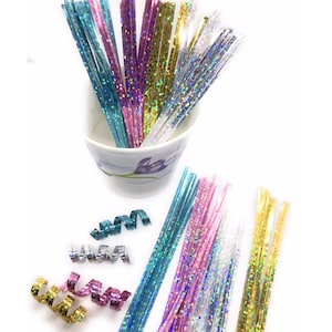 May include: Assortment of colorful iridescent metallic curling ribbon in blue, pink, gold, and silver. The ribbon is in a small white cup and some are curled on a white surface.