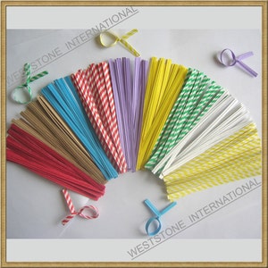 May include: Assortment of colorful paper twist ties in various patterns, including red and white stripes, green and white stripes, yellow and white stripes, and solid colors like blue, purple, and yellow. The twist ties are arranged in a fan shape on a white background.