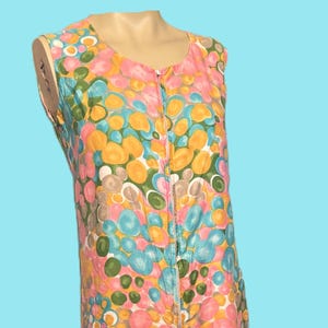 May include: A sleeveless jumpsuit featuring a vibrant pattern of pink, yellow, blue, and green circles. The vintage garment has a zip down the front and wide legs. The jumpsuit is made of a lightweight fabric.
