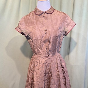 May include: A brown vintage dress with a white collar and short sleeves. The dress has a fitted bodice and a full skirt with a quilted pattern.